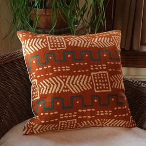Printed Mudcloth pillow cover in orange and turquoise.