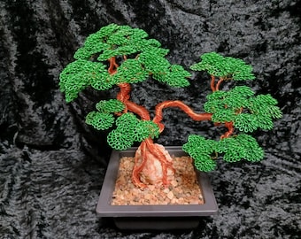 Puede incluir: Escultura artesanal de un bonsái de alambre. El árbol presenta un tronco y ramas de color cobre, con hojas de alambre verde vibrante. Está colocado en una maceta cuadrada gris llena de pequeñas piedras, creando un paisaje en miniatura.