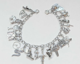 May include: A silver charm bracelet with various charms, including a snake, a sword, a crown, a shoe, a key, a horse, a book, a helmet, a fan, and a charm that says "NEW YORK".