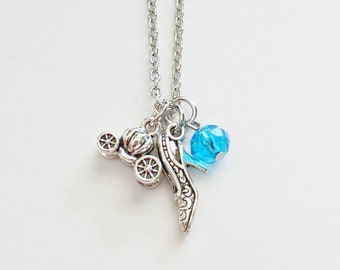 May include: A silver necklace with a charm of a glass slipper, a carriage, and a blue crystal bead.