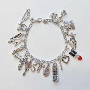 May include: A silver charm bracelet with various charms, including a lipstick, a heart, a phone, a hair dryer, a comb, a shoe, a car, a purse, a bow, and a tag that says "Best Friends".