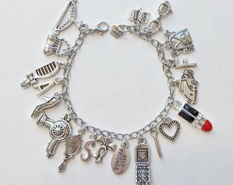 May include: A silver charm bracelet with various charms, including a lipstick, a heart, a phone, a hair dryer, a comb, a shoe, a car, a purse, a bow, and a tag that says "Best Friends".
