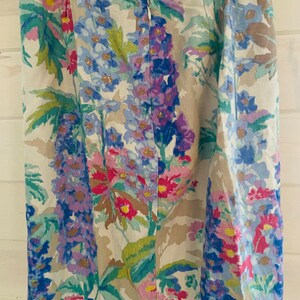 May include: A beige skirt with a floral print featuring pink, blue, and green flowers. The skirt has a zipper closure and a waistband with the text "Parterre Fleuri" in green.