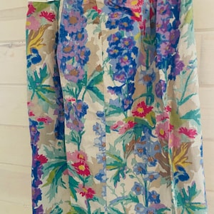 May include: A beige skirt with a floral print featuring blue, purple, pink, and green flowers. The skirt has a waistband with the text "PARTERRE FLEURI" in green.
