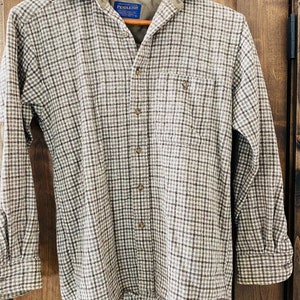 May include: A brown and white plaid flannel shirt with a blue Pendleton label. The shirt has a button-down collar and long sleeves.