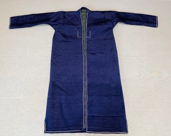 May include: A long, dark blue robe with a green lining and white stitching. The robe has long sleeves and a collar.