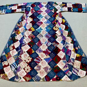 May include: A colorful patchwork coat with a diamond pattern. The coat features a variety of squares in shades of blue, red, white, and yellow. The squares are decorated with floral and geometric designs. The coat has long sleeves and a wide skirt.