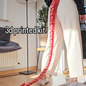 Może przedstawiać: Czerwony ogon wydrukowany w 3D, ze spiczastym końcem, noszony jako dodatek do kostiumu. Tekst "3d printed kit" jest widoczny na zdjęciu.