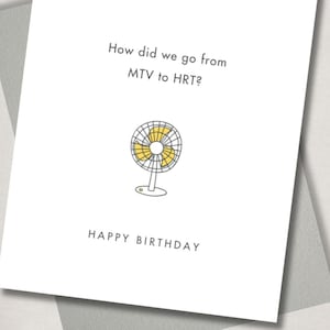 May include: A white birthday card with the text "How did we go from MTV to HRT?" and "HAPPY BIRTHDAY". The card features a yellow and gray illustration of a fan.