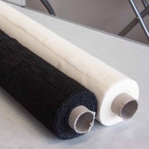 Pode incluir: Dois rolos de tecido, um preto e um branco, estão enrolados e prontos para serem usados em projetos de costura.