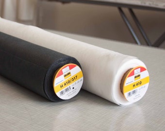 May include: Two rolls of white and black fabric with yellow labels. The labels read "Wissene H 410/317 100% PL 300 gr/m2 90 cm x 25 m" and "Wissene H 410 100% PL 300 gr/m2 90 cm x 25 m".