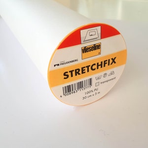 May include: A roll of white fabric with a circular label. The label is orange and red with the text "STRETCHFIX" and "vlieseline". The roll is 30 cm wide and 5 m long.