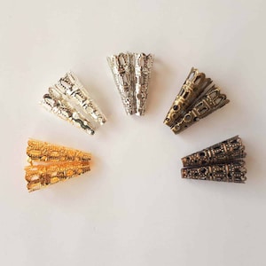May include: Assortment of metal cone-shaped bead caps in gold, silver, and bronze. The caps have an intricate, decorative design.