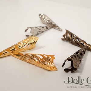 May include: Five decorative metal tips in gold, silver, and bronze. The tips are shaped like a pointed cone with an intricate, openwork design.