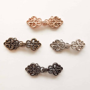 May include: Three ornate metal clasps in different finishes: gold, silver, and bronze. Each clasp features a decorative, intricate design with a hook and loop closure.