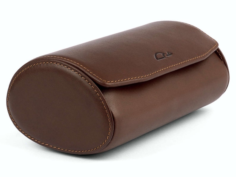May include: A brown leather watch roll with a stitched seam and a small logo on the top.