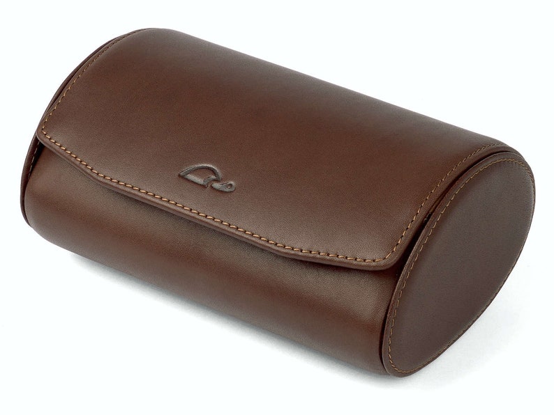 May include: A brown leather watch roll with a stitched seam and a small logo on the top.