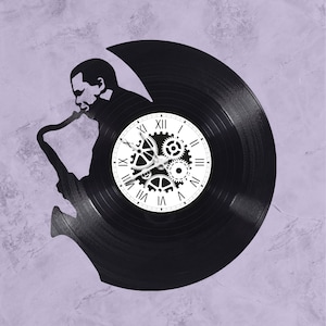 May include: A black vinyl record clock with a silhouette of a person playing a saxophone. The clock face features Roman numerals and gears.