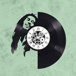 May include: A black vinyl record clock with a white clock face and Roman numerals. The clock face has a design of gears and is set against a silhouette of Bob Marley's face.