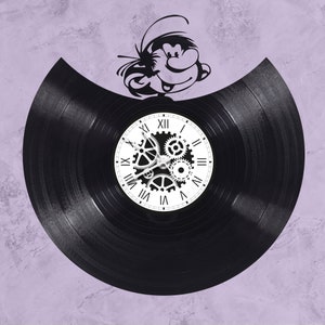May include: A black vinyl record clock with a white face and gears. The clock is decorated with a black and white cartoon character.