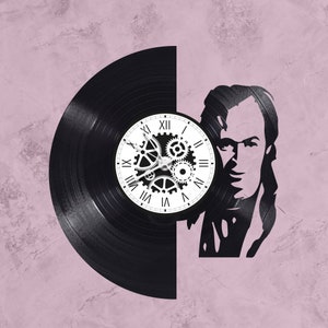 Peut inclure: Une horloge en vinyle noir avec un cadran blanc et des engrenages. Le cadran de l'horloge comporte des chiffres romains et les engrenages sont argentés. Le disque est découpé en forme de tête humaine.