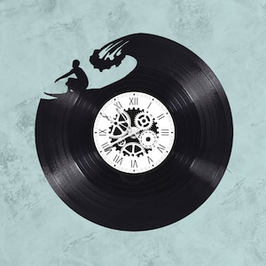 May include: A black vinyl record clock with a white clock face and gears. The clock is shaped like a wave with a silhouette of a surfer riding the wave.