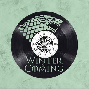 May include: A black vinyl record clock with a white clock face and a gear design. The record has a black and white image of a direwolf head with the words "Winter is Coming" printed below the clock face.