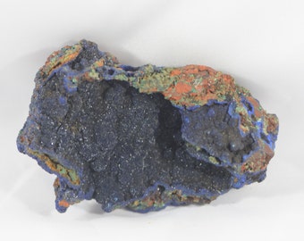 May include: Azurite mineral specimen with a blue, green, and orange color scheme. The mineral has a rough, textured surface and a hollow center.