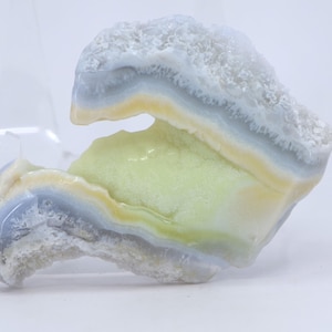 Pu&ograve; includere: Un'agata blu chiaro, gialla e verde con un motivo unico a strati. L'agata ha una texture ruvida e naturale ed &egrave; un bellissimo esempio di questo tipo di pietra preziosa.