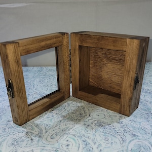 May include: A wooden box with a hinged lid and a glass front. The box is stained a dark brown color and has a rustic look. The box is open and empty.
