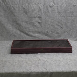 May include: A dark wood display case with a glass top. The case has a hinged lid and a lock.