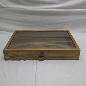 May include: A wooden display case with a glass top and a lock. The case is made of light brown wood and has a natural finish.