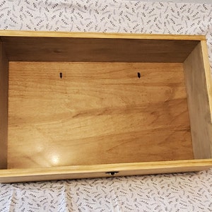 May include: Empty wooden box with a drawer. The box is made of light wood and has a natural finish. The drawer is closed and has a small metal handle.