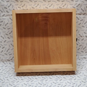 May include: A wooden drawer box with a light brown finish. The drawer box is empty and has a simple design.