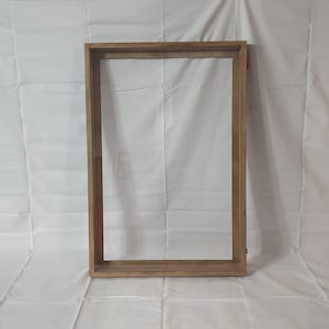 May include: A wooden picture frame with a clear glass insert. The frame is a light brown color and has a simple design.