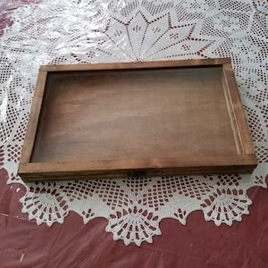 May include: A wooden shadow box with a glass front. The box is stained a dark brown color and has a simple design.