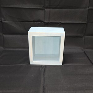 May include: A light blue wooden shelf unit with a single open shelf. The shelf is made of wood and has a light blue paint finish.