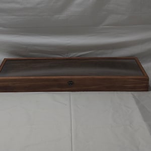 May include: A wooden display case with a glass top and a metal latch. The case is made of dark wood with a natural grain.