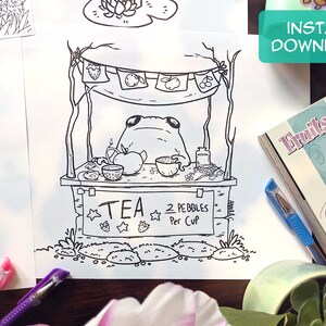 May include: A black and white line drawing of a frog sitting at a tea stand. The stand has a sign that says "TEA 2 PEBBLES Per Cup".