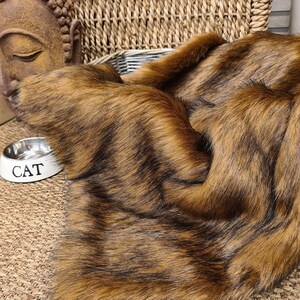 May include: A brown and black faux fur throw blanket with a soft, fluffy texture.