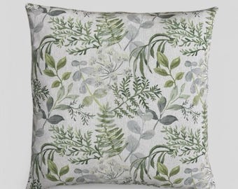 Könnte beinhalten: Ein quadratisches Kissen mit weißem Hintergrund und einem grünen Blumenmuster. Das Muster zeigt verschiedene Blätter und Farne in Grüntönen.