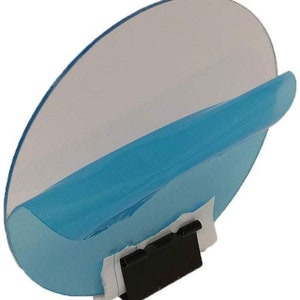 May include: A blue and clear plastic car blind spot mirror with a black clip. The mirror is designed to be attached to the inside of a car window.