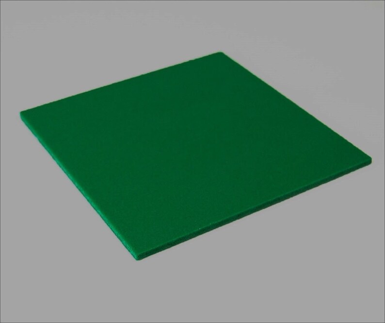 May include: A square, solid green object with a textured surface. The object is positioned at a slight angle against a neutral grey background, showcasing its form and colour.