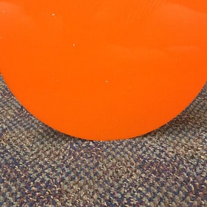 May include: A bright orange round disc with the text "SIBE POLYMERS" printed in black.