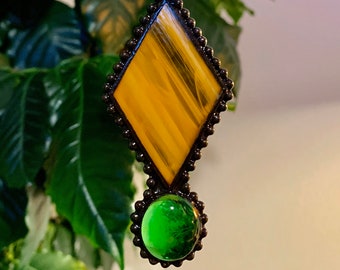 May include: A stained glass suncatcher with a diamond-shaped yellow and orange piece and a round green piece hanging from a chain.