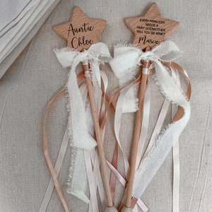 Puede incluir: Dos varitas de madera en forma de estrella con mangos de madera clara. Una est&aacute; grabada con "Auntie Chloe" y la otra con "EVERY PRINCESS NEEDS A FAIRY GODMOTHER. WILL YOU BE MINE?" y "Marcie". Ambas tienen lazos de cinta blanca deshilachada y cintas largas.