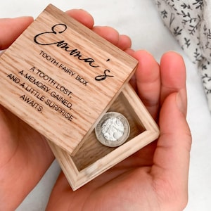 Puede incluir: Una caja de madera para el hada de los dientes con la inscripción "Emma's Tooth Fairy Box" y el texto "A tooth lost, a memory gained, and a little surprise awaits."