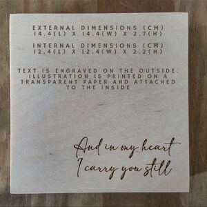 May include: A wooden box with the text "And in my heart I carry you still" engraved on the front. The box measures 14.4 inches long, 14.4 inches wide, and 2.7 inches high. The inside dimensions are 12.4 inches long, 12.4 inches wide, and 2.2 inches high.
