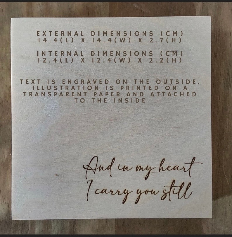 May include: A wooden box with the text "And in my heart I carry you still" engraved on the front. The box measures 14.4 inches long, 14.4 inches wide, and 2.7 inches high. The inside dimensions are 12.4 inches long, 12.4 inches wide, and 2.2 inches high.