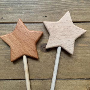 Puede incluir: Dos varitas con forma de estrella hechas de madera. Una estrella est&aacute; elaborada con madera de color marr&oacute;n rojizo oscuro, mientras que la otra es de madera de color beige claro. Cada estrella est&aacute; unida a un mango cil&iacute;ndrico de madera.